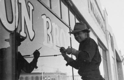 Don painting a wall sign at unknown location, c. 1956