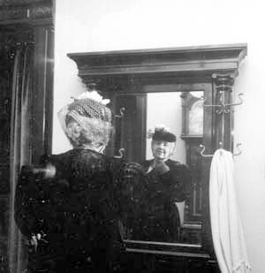 Woman in period dress at hall tree mirror
