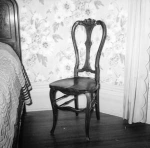 Wooden chair in northeast corner next to bed