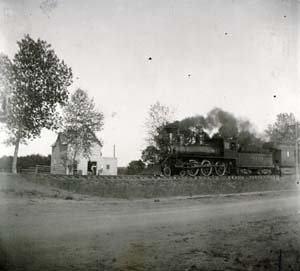 Colorado and Southern train westbound from Greeley passing Hoffman Mill on Riverside Avenue, J.M. Hoffman in doorway, c. 1894